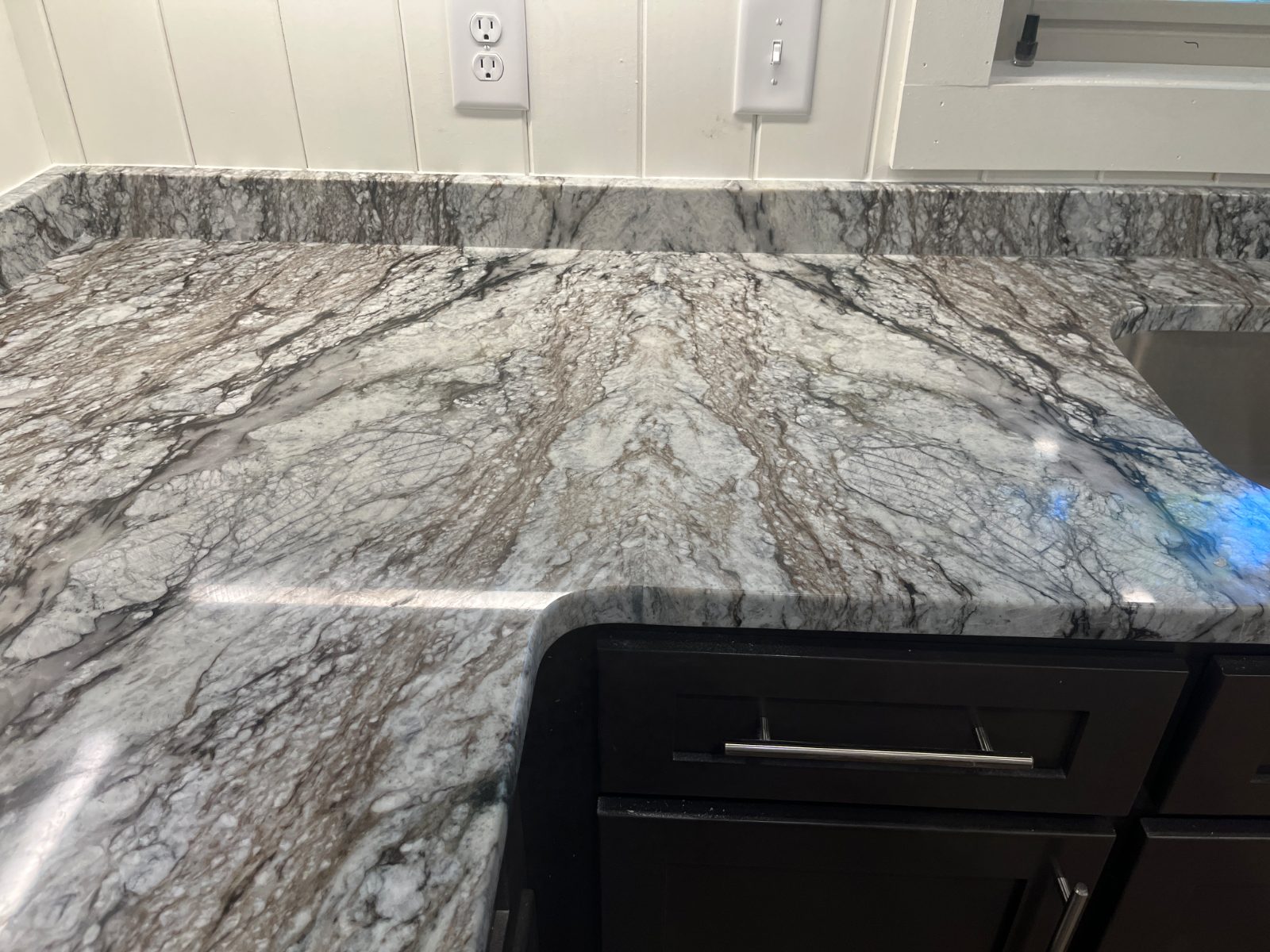 Blue Dunes kitchen countertop installed in Franklin, NC: close-up of a counter corner with backsplash beside an undermount sink