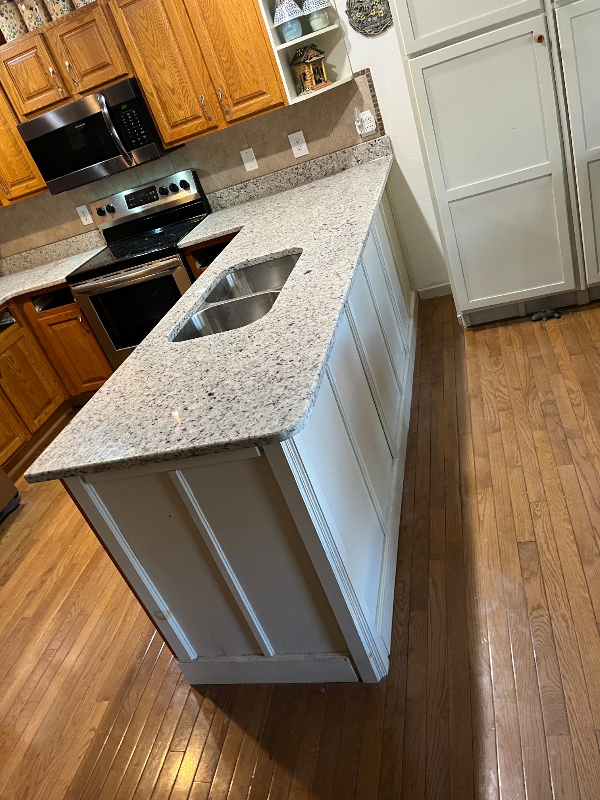 Kitchen countertop installed in Murphy, NC: Peninsula with a double undermount sink facing a range and microwave