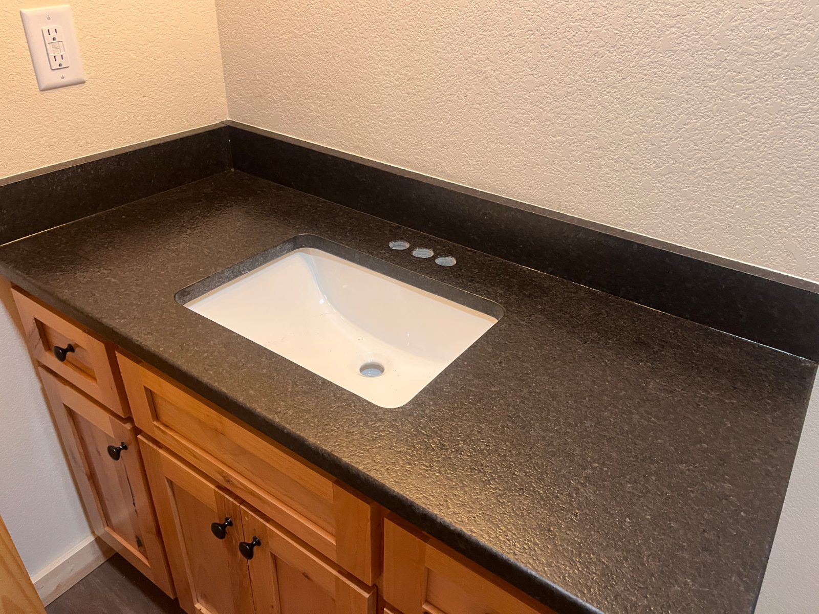 Black Pearl, leathered bathroom vanity countertop installed in Murphy, NC: single vanity with an undermount sink and short backsplash over wood cabinets