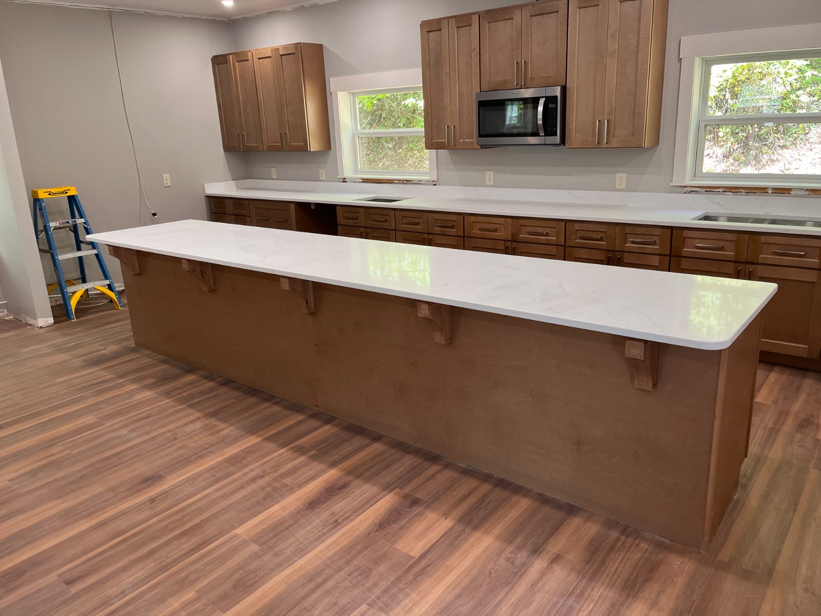 Calacatta Rusta kitchen countertop installed in Murphy, NC: Long island bar with corbels facing a perimeter run with two sinks