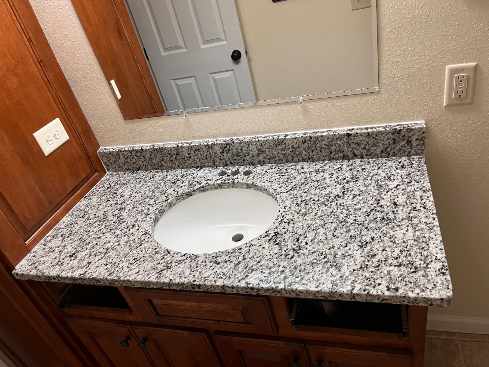 Luna Pearl bathroom vanity countertop installed in Warne, NC: single bathroom vanity with an oval undermount sink and backsplash